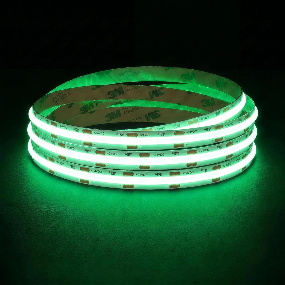 Green SCOB LED strip coil illuminated on a dark background, 24V DC and 10mm wide, with copper connection pads