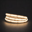 Warm white 3000K COB LED strip illuminated in a coil on a dark background