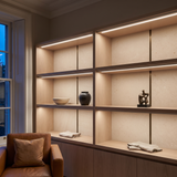 4000k white dot-free LED strip lighting beneath smoked-oak display shelving in a residential drawing room