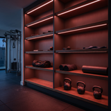 Red dot-free LED strip lighting beneath graphite-oak equipment shelves in a private gym