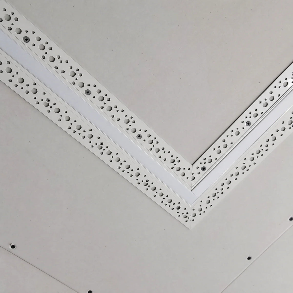 Straight plaster-in profile screwed into a plasterboard ceiling at a mitred corner before skimming