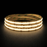 Warm White 2700K 24V 10mm COB LED strip shown illuminated in a coil on a dark background.