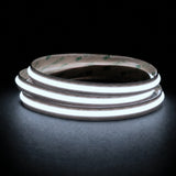 Cool White 6500K Free Cut COB LED strip coil illuminated on a dark background, 24V DC and 10mm wide.