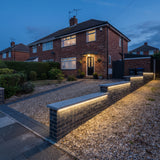 Soft pale-yellow RGB mixed light beneath every stepped driveway wall coping