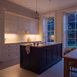 Warm White 3000K SCOB LED strip lighting beneath wall cabinets in a large British kitchen in the evening; installation illustration.
