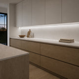 Illustrative oak-and-stone kitchen with neutral-white 4000K SCOB LED lighting beneath wall cabinets over a dry preparation counter.