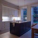 Daylight 5000K SCOB LED strip lighting beneath wall cabinets in a large British kitchen in the evening; installation illustration.