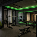Illustrative strength gym with green SCOB LED ceiling accents and mirror lighting above weights and exercise benches