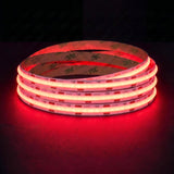 Red SCOB LED strip coil illuminated on a dark background, 24V DC and 10mm wide, with copper connection pads