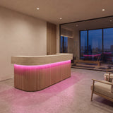 Pink SCOB LED strip lighting beneath a curved gym reception counter, with a Pilates room beyond; installation illustration.