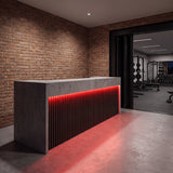 Red SCOB LED strip lighting beneath a concrete and timber gym reception counter, with a training room beyond; installation illustration.