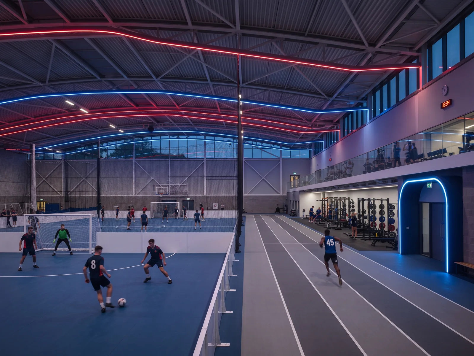 Indoor British sports complex with red and blue LED neon flex installed along roof beams and a curved entrance portal